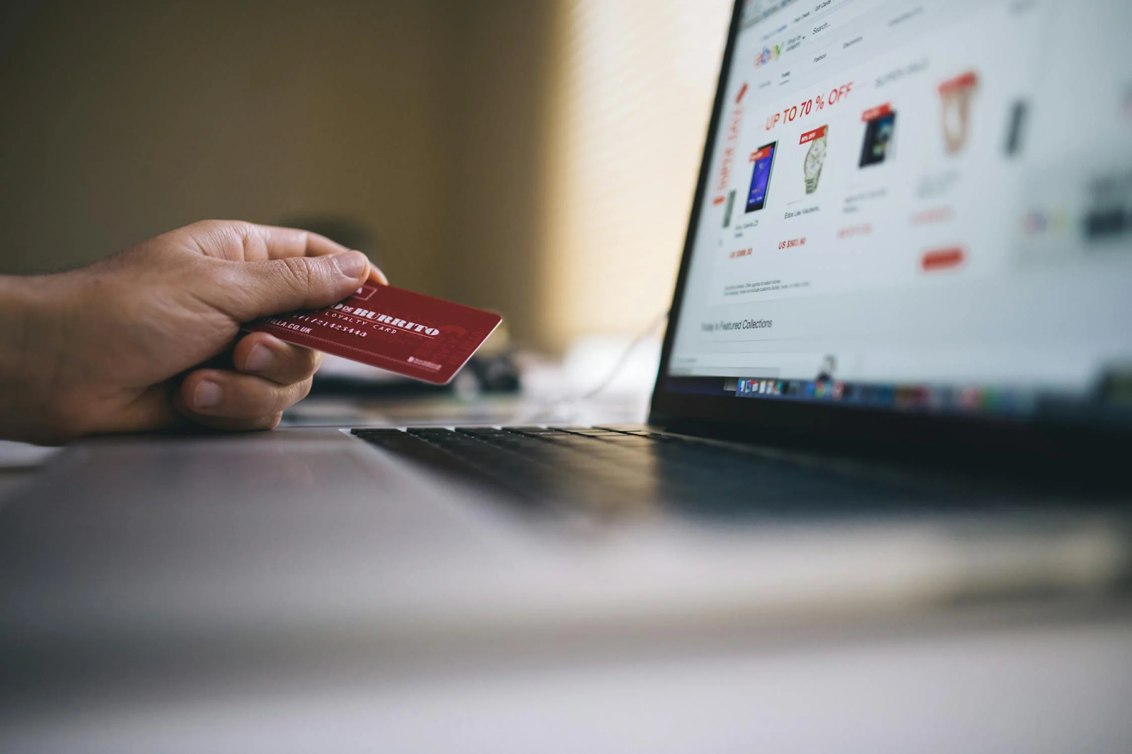 Person holding a credit card while shopping online on an eCommerce website using a laptop