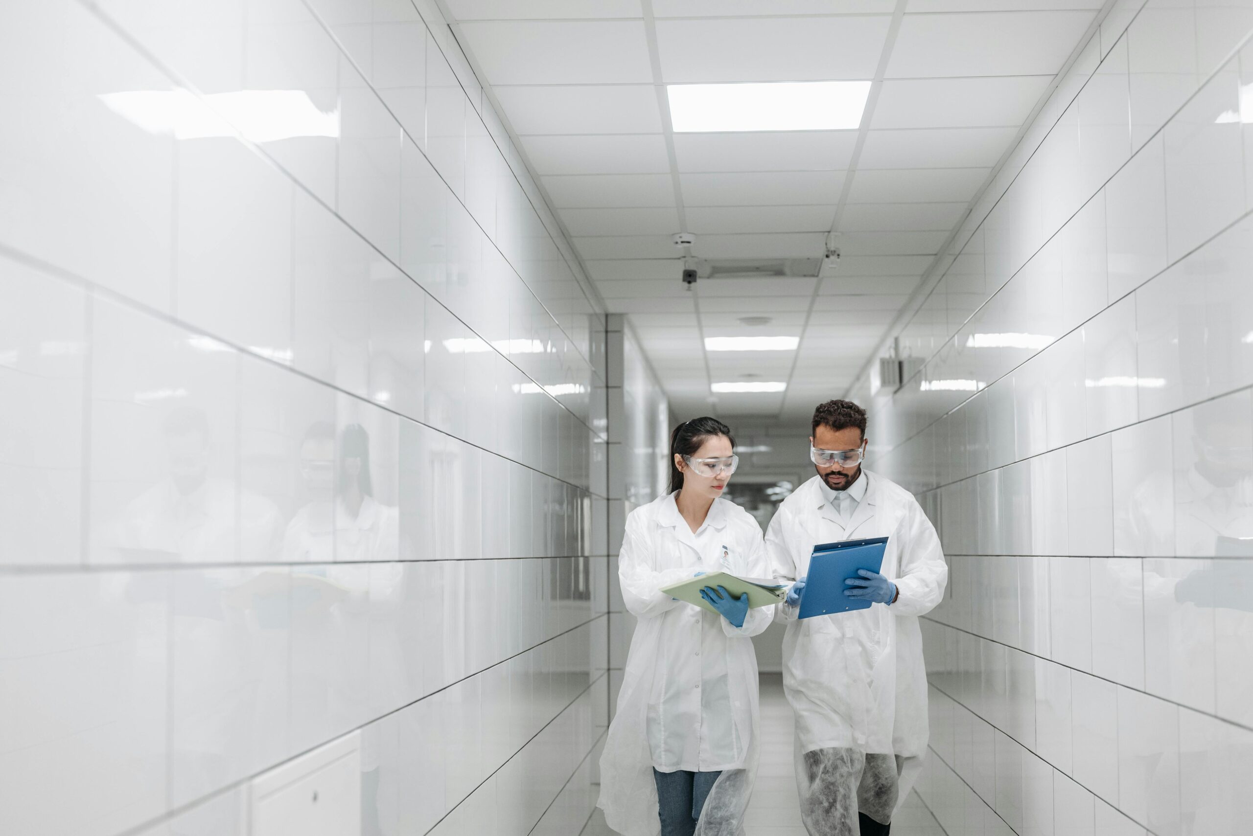 two medical professionals looking at documents while walking in a hallway